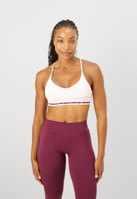 Sujetador deportivo rosa con tirantes finos, acentuado por una banda multicolor, combinado con leggings burdeos de tiro alto que presentan un pequeño logo.