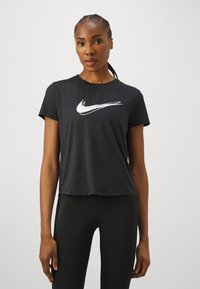 Must mustus T-särk, millel on valge Nike swoosh logo, lühikesed varrukad, ringkaelus ja lõtv istuvus, valmistatud hingavast kangast.