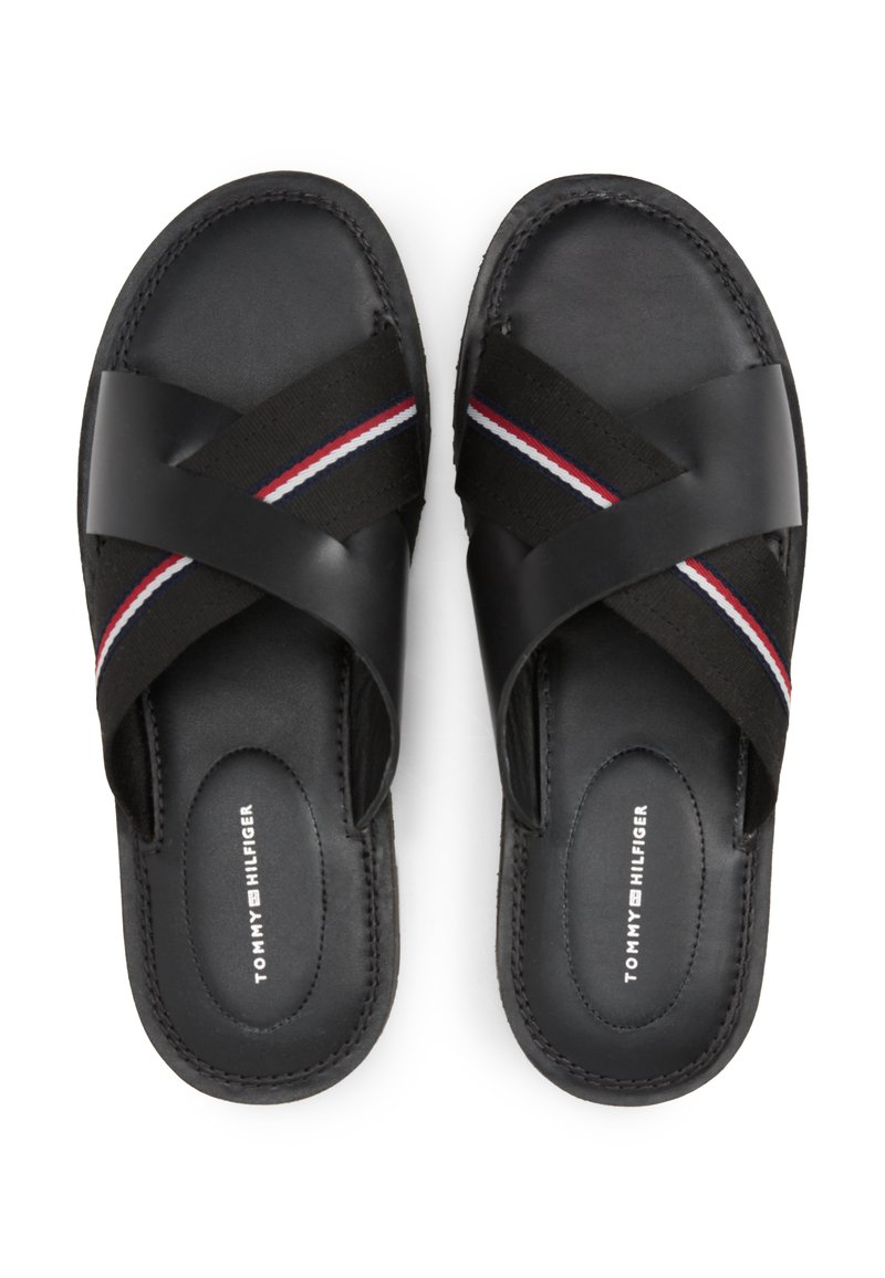 Sandalias negras con correas cruzadas, fabricadas con cuero liso y tejido elástico. Con detalles en rayas rojas, blancas y azules. Suela plana.