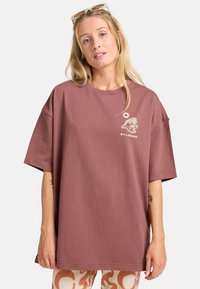 Billabong ylisuuri t-paita pölyruusussa, jossa on pyöreä pääntie, lyhyet hihat ja graafinen logosuunnittelu rinnassa. Pehmeä puuvillamateriaali.