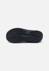 Semelle de chaussure en caoutchouc noir avec un motif de bande de roulement, présentant des rainures et des indentations circulaires pour une traction et une flexibilité optimales.