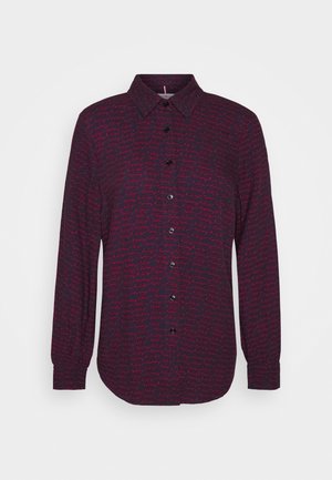 Chemise à manches longues boutonnée de couleur violet foncé avec un motif manuscrit rose répétitif. Col avec boutons noirs et manches retroussées.