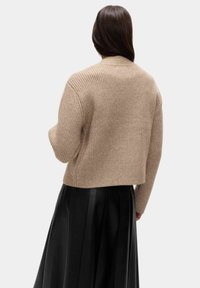 Béžový zkrácený svetr s ribkovanou texturou, dlouhými rukávy a kulatým výstřihem, vystavený na jednobarevném světlém pozadí.