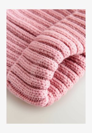 Gebreide roze beanie met ribbelstructuur. Zacht, dik garen zorgt voor een nauwsluitende pasvorm. Het omgeslagen ontwerp voegt diepte en detail toe aan het geheel.