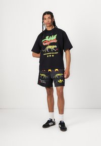 Black oversized t-shirt with colorful graphic featuring a leopard and text, paired with black shorts with yellow stars and leopard print details.