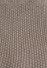 Dzianina w beżowo-brązowym kolorze o prążkowanej fakturze; równomiernie rozmieszczone, delikatne pionowe linie tworzą subtelny wzór.