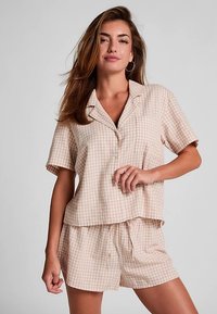 Beige geruite pyjama set met korte mouwen, bestaande uit een knoopsluitend shirt en een short met trekkoord, gemaakt van zachte, lichtgewicht stof.