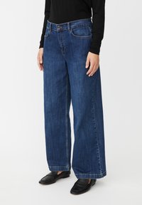 Jeans de pierna ancha en denim azul oscuro, con cintura alta, bolsillos delanteros y cierre de botón. Textura suave con un acabado limpio.