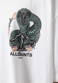 Tricou alb cu un design de piele de șarpe în verde și negru, înconjurat de accente florale în roz și galben, cu textul "ALLSAINTS" dedesubt.