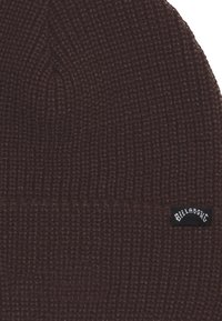 Ruskea neulepipo, jossa on uritettu pinta ja käännetty reuna. Sivussa on pieni musta Billabong-tunnus ommeltuna.