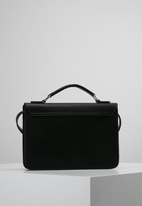 Borsa in pelle nera con design strutturato, manico superiore e anelli laterali. Texture liscia con patta anteriore e minimi accenti hardware.