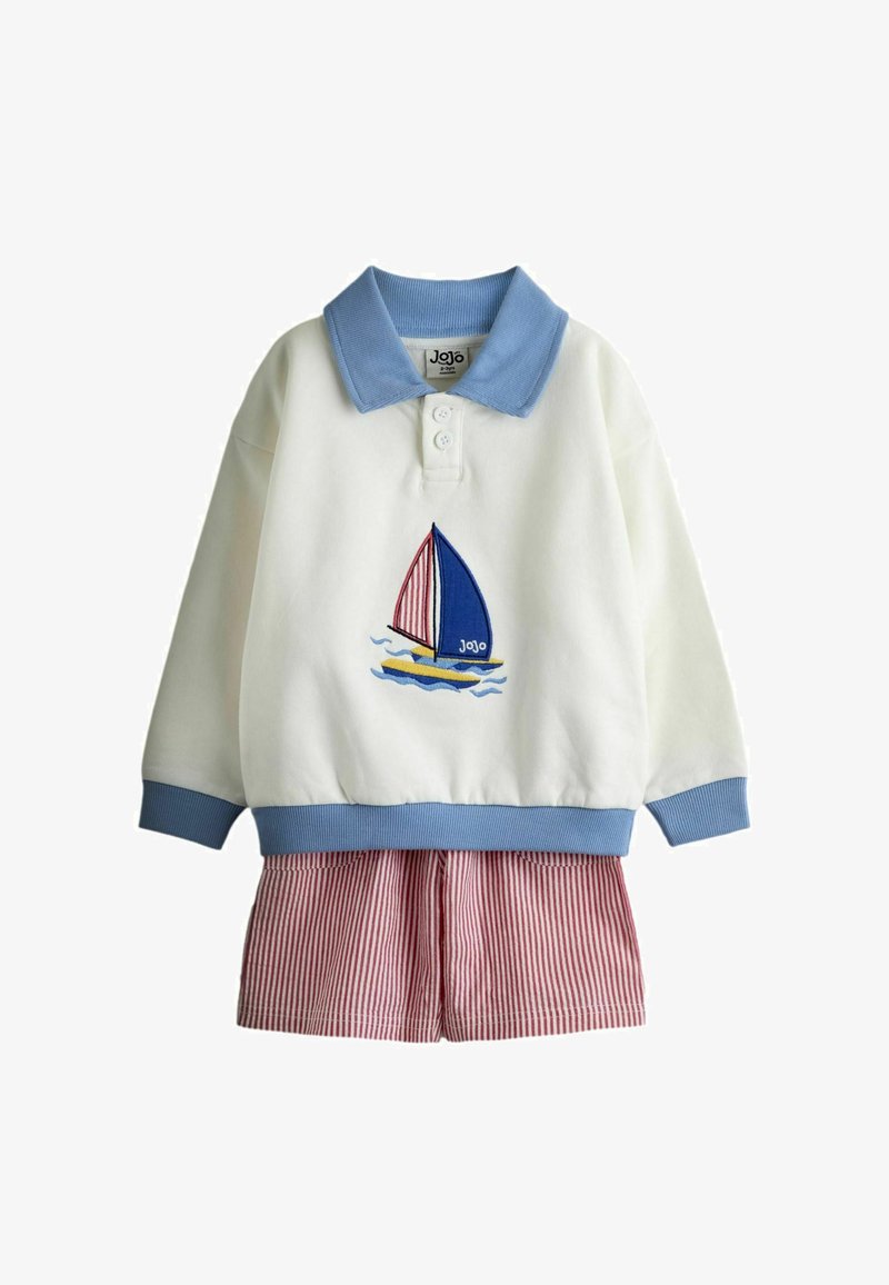 Valge pikemate varrukatega särk sinise krae ja varrukaservadega, millel on purjekala tikand, sobitatud punaste ja valgete triibuliste pükstega.