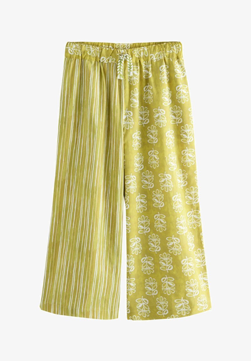Pantalon jaune à jambes larges avec une taille élastique et un cordon blanc, comportant des rayures verticales sur une jambe et des motifs de feuilles blanches sur l'autre.