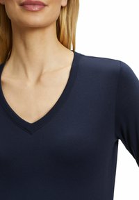 Navyblaues V-Ausschnitt-Oberteil mit langen Ärmeln, aus einem glatten, dehnbaren Material gefertigt. Verfügt über einen klaren Ausschnitt und eine körpernahe Passform.