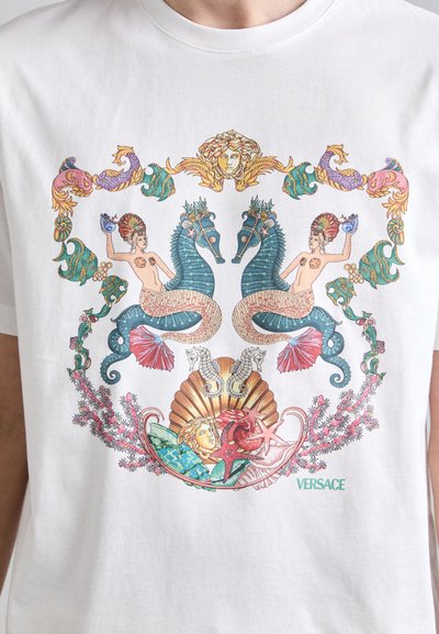 Witte katoenen T-shirt met een kleurrijk bedrukt ontwerp met zee-thema motieven, waaronder zeemeerminnen, zeepaardjes en schelpen, samen met de tekst "VERSACE".