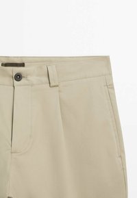 Pantaloni beige con design a vita piatta, chiusura con bottone nero e passanti per cintura. Tessuto liscio con dettagli di cucitura accurati.
