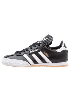 Schwarze Ledersneaker mit weißen Streifen, strukturiertem Gummisohle und gepolstertem Zungenbereich. Mit "Samba"- und Adidas-Branding in Gold.
