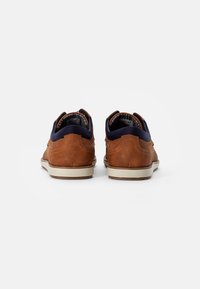 Brune semskede sneakers med marineblå detaljer ved kraven, beige gummisål, tekstureret bagdel og mønstret indvendig foring.