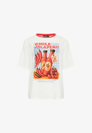 Hvid T-shirt med rød krave med grafik af jalapeño-peberfrugter, flasker med hot sauce, tomater og tekst om stærk chili og naturlig oprindelse.
