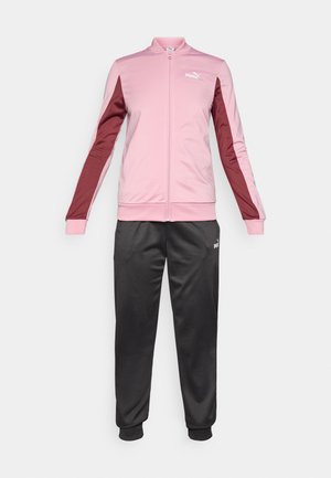 Puma Trainingsjacke in hellrosa mit kastanienbraunen Akzenten, Reißverschluss vorne und hohem Kragen, kombiniert mit schwarzen Sweatpants, elastischen Bündchen und Bund.