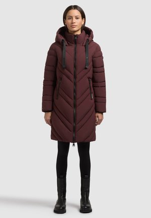 Geacă pufoasă burgundy cu un design în formă de v arh, fermoar frontal, glugă ajustabilă și curele negre. Purtați cu leggings negri și cizme până la gleznă.