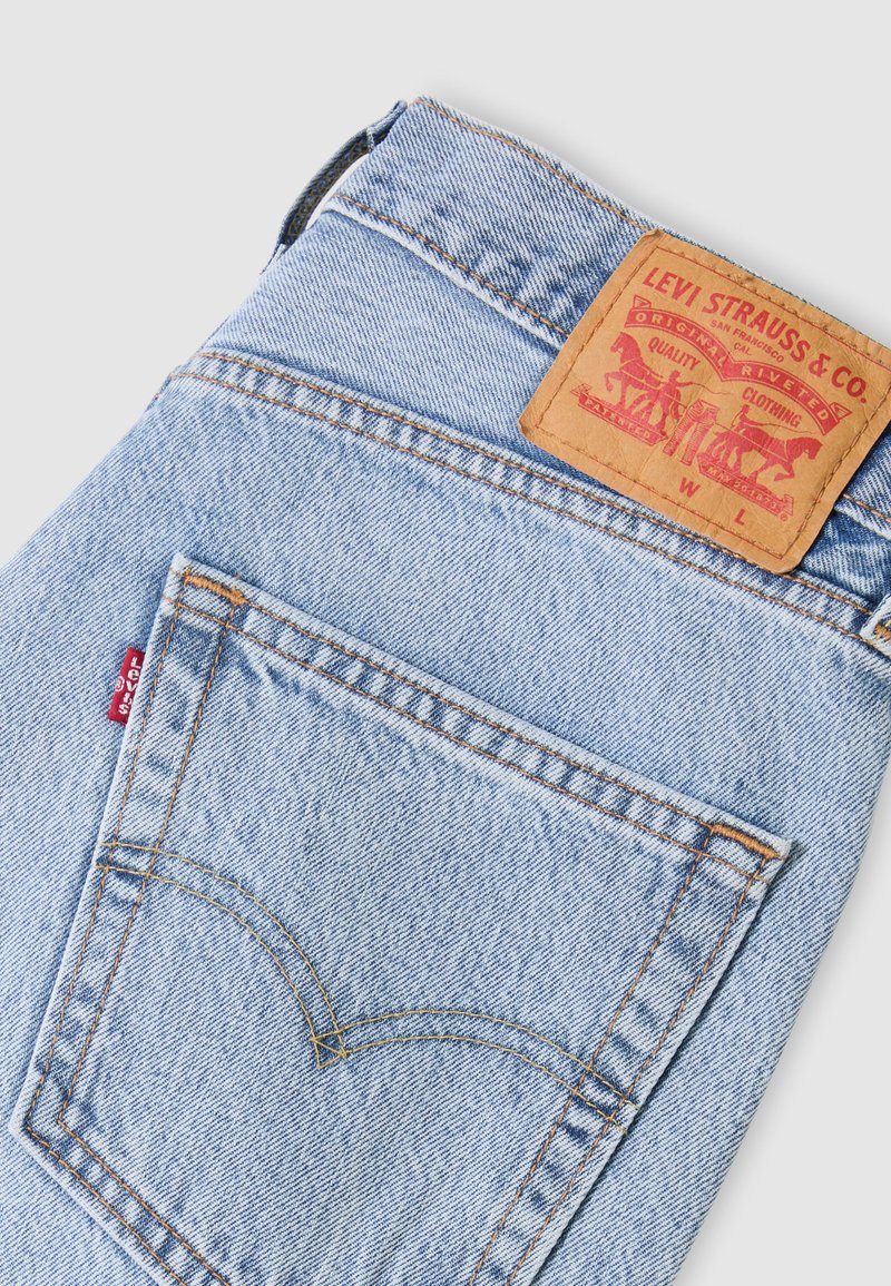 Hellblaue Jeans von Levi's, gefaltet, sodass die Gesäßtasche mit der charakteristischen Bogennaht, dem roten Label und der beigefarbenen Leder-Markenetikette sichtbar ist.