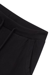 Pantaloni della tuta neri con vita elasticizzata, chiusura con lacci e tasche laterali; realizzati in morbido cotone con una texture liscia.
