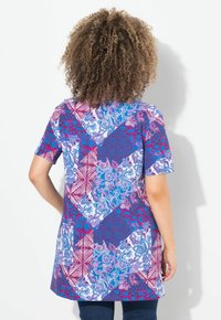 Kortærmet tunika med patchworkdesign, der har blå og røde geometriske og blomster mønstre; lavet af letvægtsstof.