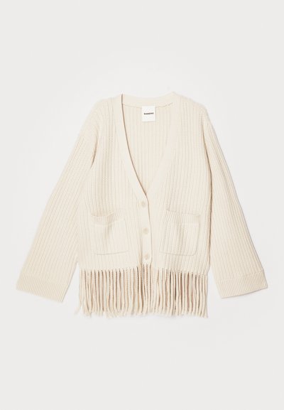 Κρέμα χρώματος πλεχτό καρδιγκάνι με V-λαιμόκοψη, τρία τέταρτα μανίκια, δύο μπροστινές τσέπες και κρόσια στο στρίφωμα.