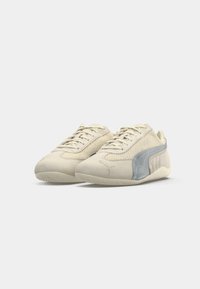 Et par beige ruskindsneakers med mesh-paneler og grå Puma-logo på siderne, vist mod en ensfarvet hvid baggrund.