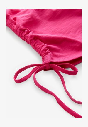 Fuchsia tyg med rynkig textur och ett par tunna band i ändarna. Mjuk, lätt material med en slät yta.