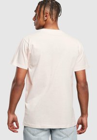 Light pink short-sleeve t-shirt featuring a classic crew neck and a relaxed fit. Material appears soft with a smooth texture.