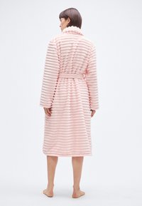 Halat de baie roz din pluș, cu textură cu dungi, mâneci lungi și centură. Material moale și design până la genunchi pentru confort.