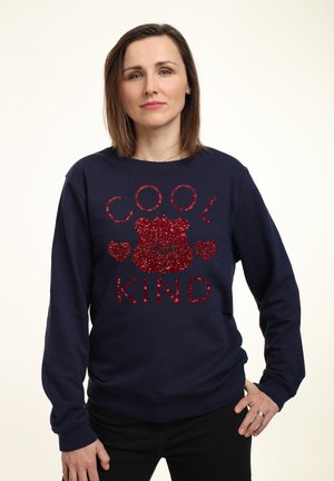 Marine sweatshirt met rode glitters tekst "COOL" en "KIND" met een beerafbeelding en hartjes, gemaakt van zachte stof met lange mouwen.