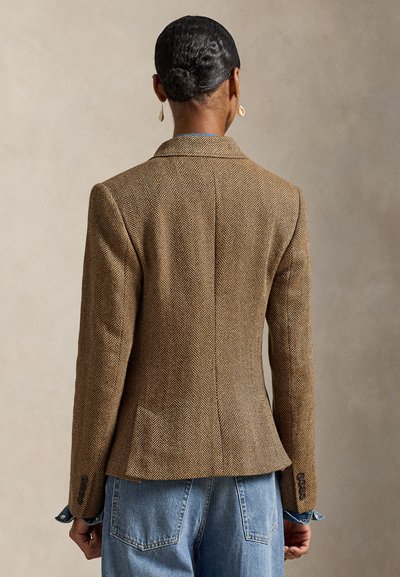 Καφέ σακάκι με ψαροκόκαλο, με δομημένους ώμους και αιχμηλές πέτρες. Διαθέτει εφαρμοστή γραμμή, υφασμάτινη υφή και διακριτικές κουμπωτές λεπτομέρειες.