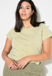 Camiseta de manga corta verde claro con brillantes decorativos dispersos en la parte frontal; tela suave, corte relajado, escote redondo.