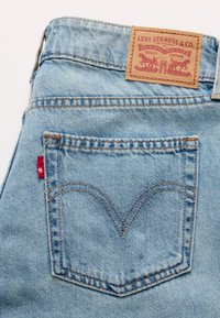 Τζιν παντελόνι από ανοιχτό μπλε τζην ύφασμα με καφέ δερμάτινο ταμπελάκι με την επιγραφή "Levi Strauss & Co." και κόκκινη ετικέτα στην πίσω τσέπη. Διαθέτει κλασικές ραφές.