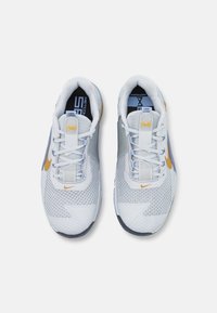 Bílé sportovní boty s prodyšným svrškem, modrými akcenty a zlatým logem Nike. Mezi funkce patří šněrovací design a textured (texturovaná) podrážka.