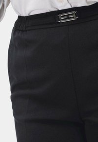 Zwarte op maat gemaakte broek met een gladde textuur, voorzien van een elastische tailleband en een metalen zilveren gespdetail.