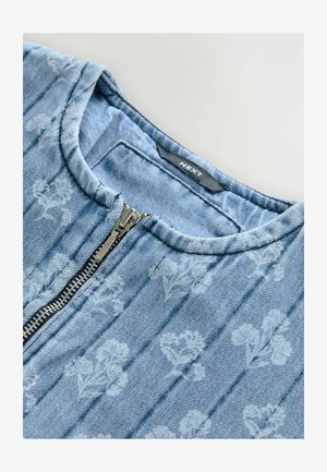 Džínová vesta v svetlo modrej farbe s tonálnym kvetinovým vzorom. Obsahuje zips a prešívanú textúru s okrúhlym výstrihom. Viditeľná značka výrobcu.