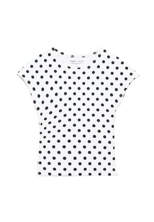 Camicia bianca a maniche corte con pois neri, scollo rotondo e linea leggermente aderente, distesa su uno sfondo bianco.