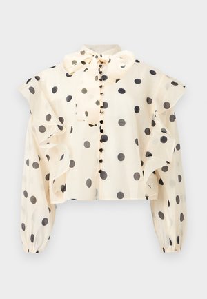 Blouse crème à pois noirs, manches volantées, boutons recouverts de tissu, manches longues bouffantes et col à nouer.