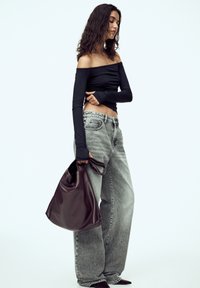 Sort off-shoulder top, høj talje lysegrå baggy jeans og en mørkebrun lædertaske med en blød tekstur og samlet detalje.