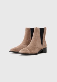 Botines de ante beige con punta afilada, paneles laterales elásticos y un tacón bajo tipo bloque. Textura suave con detalles de costura mínimos.