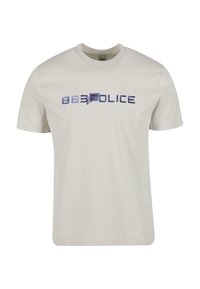 Svijetlo bež majica s kratkim rukavima napravljena od pamuka, s velikim plavim grafičkim dizajnom '88 Policija' na prednjoj strani. Ima okrugli izrez.
