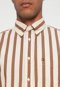 Braun- und cremefarbener gestreifter Hemd mit Button-Down-Kragen, verfügt über eine Brusttasche und Logo-Akzent. Hergestellt aus Baumwollstoff mit strukturierter Oberfläche.