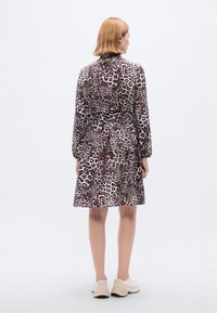 Φόρεμα με σχέδιο λεοπάρ, μακριά μανίκια, εφαρμοστή μέση, φούστα σε σχήμα καμπάνας και συνδυασμό σκούρων μπορντό και μπεζ τόνων. Υφή λείου υφάσματος.