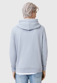 Felpa con cappuccio in cotone azzurro chiaro, con polsini e orlo a costine, dotata di tasca a marsupio e una consistenza morbida. La vista posteriore mostra la semplicità del design.