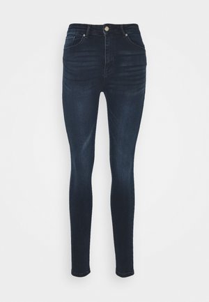 Jeans skinny feitos de denim azul escuro. Design de cintura alta com estilo de cinco bolsos e uma textura ligeiramente desbotada nos joelhos.