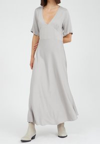 Ljusgrå, ankellång klänning med djup V-ringning, korta ärmar och en figurnära bodice som övergår i en flödande kjol. Slät textur.